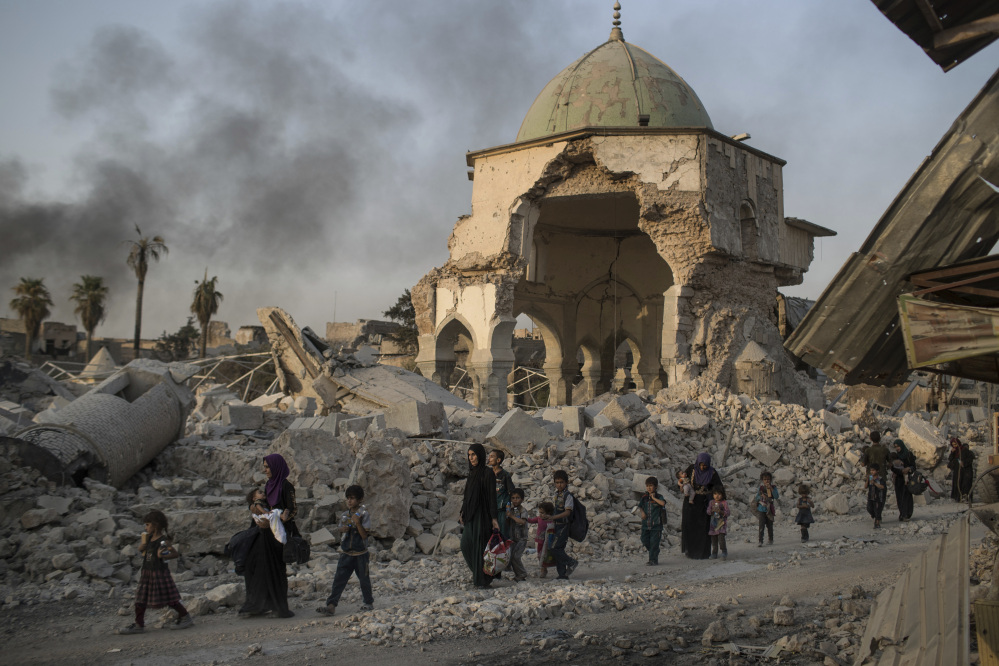 Fleeing Iraqi civilians pass a damaged mosque in Mosul earlier this week. After years of training by a U.S.-led coalition, Iraqi security troops still struggle to hold liberated territory.