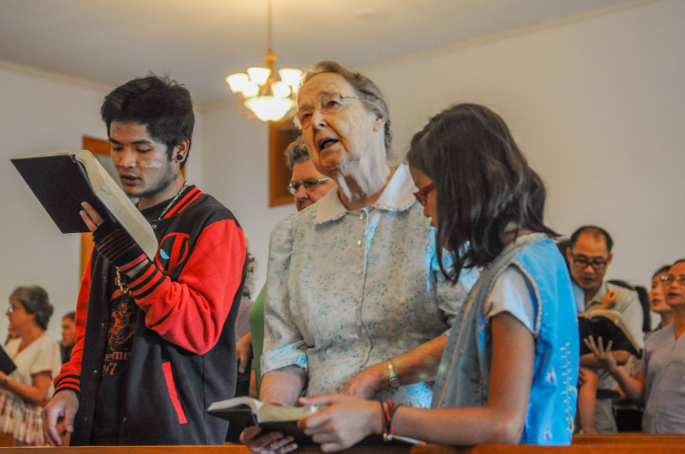 Miriam Charles, center, prays beside Paday Shee, left, and Paw Shee at Habecker Mennonite Church in Lancaster, Pa. Paday, 25, and Paw, 10, are not related but are part of the group of ethnic Karen refugees from South Asia who attend the church.
