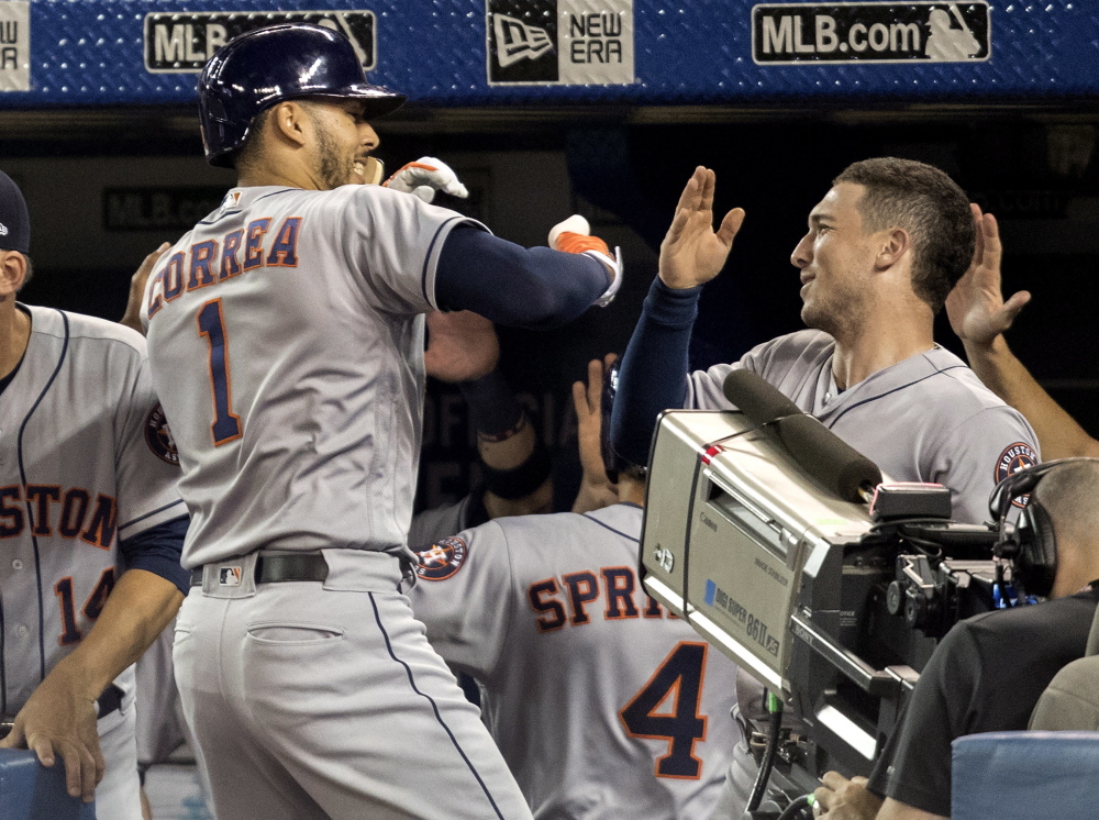 Carlos Correa of the Houston Astros is greeted by teammates Friday night after hitting a two-run homer in the first inning of a 12-2 victory against the Toronto Blue Jays.