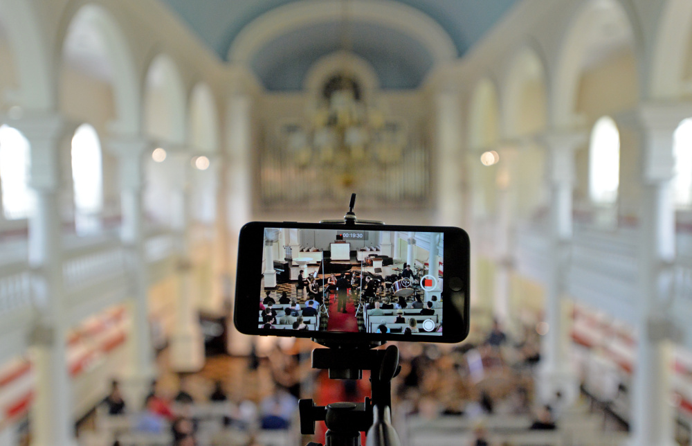 Members of the Atlantic Music Festival perform as a phone records from the balcony Saturday at Lorimer Chapel at Colby College in Waterville.