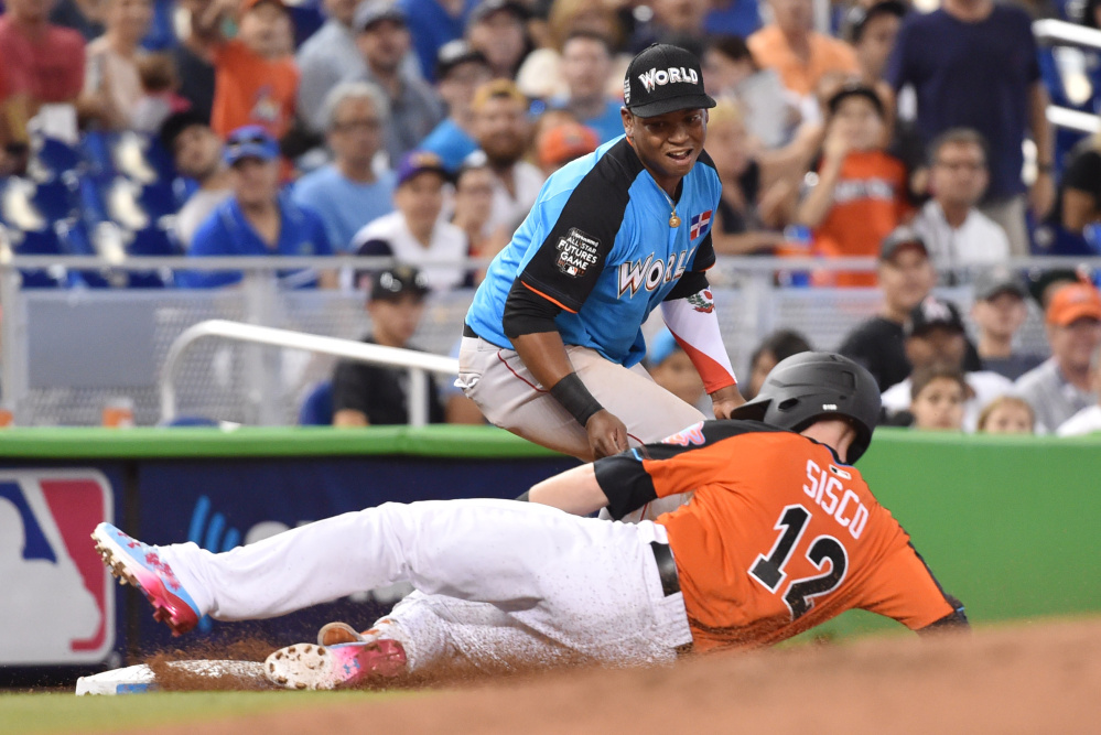 Chance Sisco of the U.S. slides past World third baseman Rafael Devers of the Portland Sea Dogs after hitting an RBI triple in the second inning during the All-Star Futures Game in Miami. The U.S. won, 7-6.