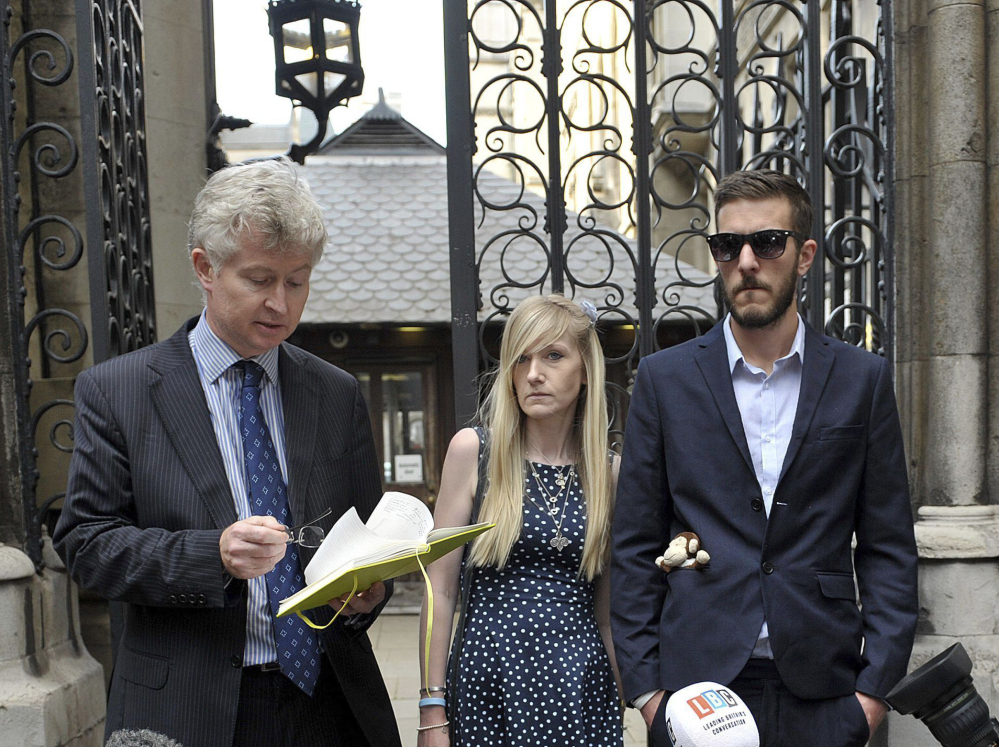 The parents of sick baby Charlie Gard, Connie Yates and Chris Gard, right, listen as a statement is read by a family friend outside the High Court in London on Monday.