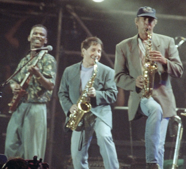 Paul Simon, center, plays a finale with lead guitarist Ray Phiri, left, and actor-comedian Chevy Chase in New York's Central Park in 1991.