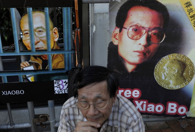 A protester sits in front of pictures of jailed Chinese Nobel Peace laureate Liu Xiaobo during a demonstration outside the Chinese liaison office in Hong Kong on Thursday.