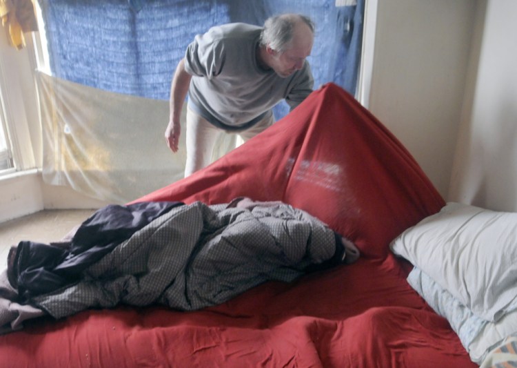 Al Sugden of Augusta searches his bedding for bedbugs in his Water Street apartment in May 2016. To help solve the city's bedbug problem, an anonymous donor has offered to put up $20,000 if others will match it.