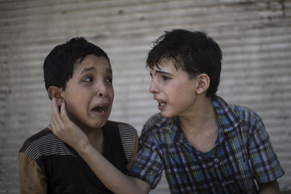 Two cousins sit outside their house after it was hit on June 24, leaving family members trapped. The psychological toll will likely be steep for residents who survived the siege. At right, Iraqi security forces celebrate their victory on July 10 over Islamic State.