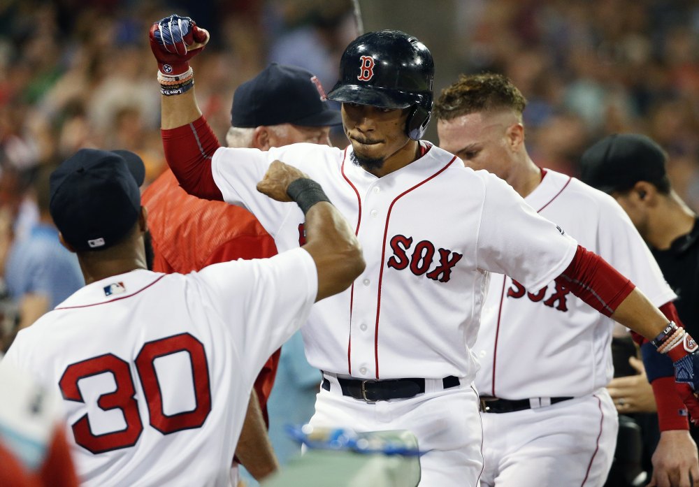 Mookie Betts, center, celebrates with Chris Young after hitting a two-run homer in the third inning Sunday night against the New York Yankees, ending a 24-inning scoreless streak for the Red Sox. Boston won, 3-0, to earn a split of the four-game series after losing 3-0 in the opener of the day-night doubleheader. Story, C5