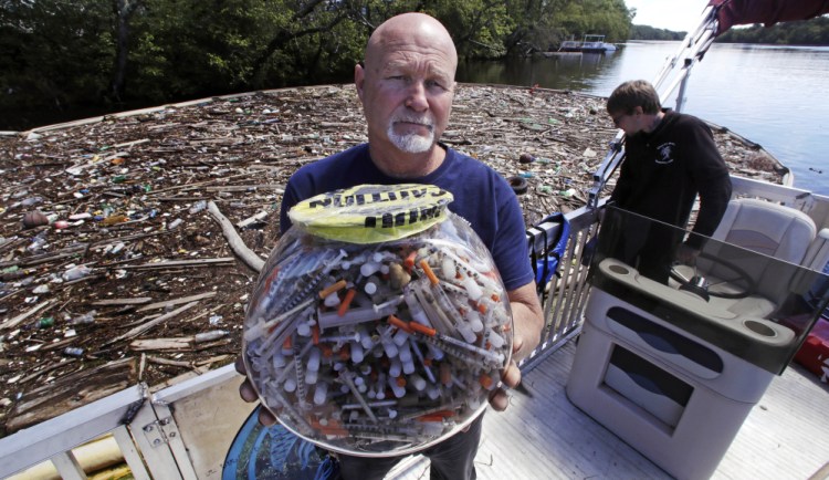 Activist Rocky Morrison of the Clean River Project holds up a fish bowl filled with syringes that were recovered during 2016 on the Merrimack River next to their facility in Methuen, Mass. Morrison leads a cleanup effort along the Merrimack River, which winds through the old milling city of Lowell, and has recovered hundreds of needles in abandoned homeless camps that dot the banks, as well as in piles of debris that collect in floating booms he recently started setting.