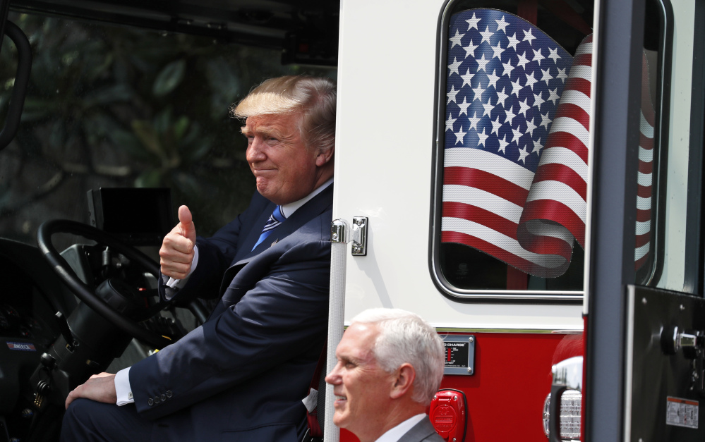 President Trump, accompanied by Vice President Mike Pence, gives a thumbs-up from the cabin of a Pierce fire truck during a "Made in America" product showcase featuring items created in each of the 50 states Monday at the White House in Washington.