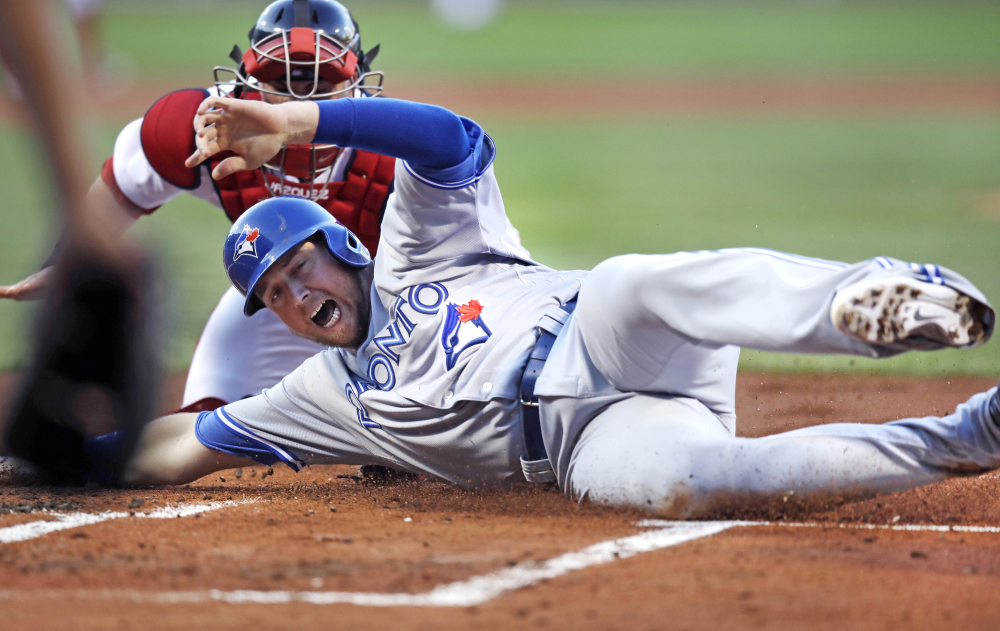 The Blue Jays' Justin Smoak beats the tag by Red Sox catcher Christian Vazquez to score on a two-run double by Kendrys Morales in the first inning.