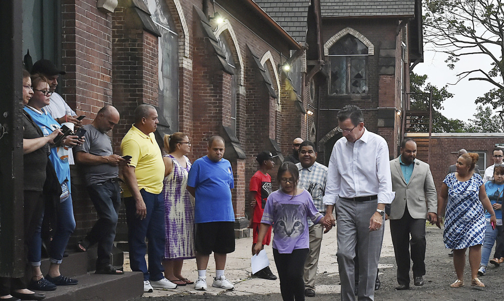 Connecticut Gov. Dannel P. Malloy walks with 9-year-old Hayley Chavarria before speaking at a Thursday news conference at Iglesia de Dios Pentecostal Church in New Haven, where her mother has taken sanctuary to avoid deportation.