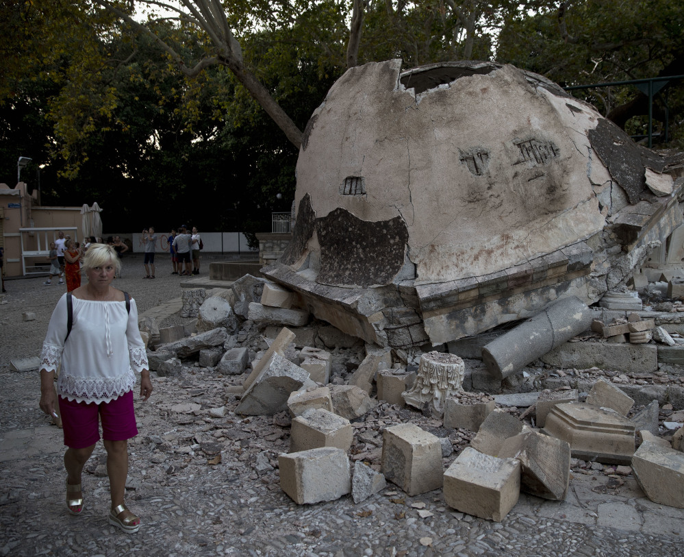 A tourist walks past a damaged structure outside a mosque after an earthquake on the Greek island of Kos. Hundreds of people on Kos spent the night sleeping outdoors.