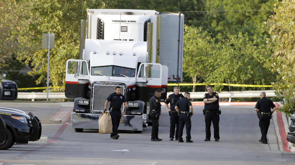 San Antonio police officers investigate the scene after eight people were found dead in a tractor-trailer.