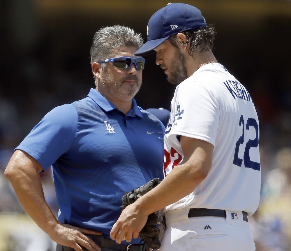 Dodgers starting pitcher Clayton Kershaw, right, talks with trainer Nathan Lucero in the second inning Sunday. Kershaw left with a back injury.