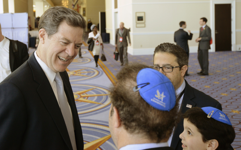 A staunch conservative, Kansas Gov. Sam Brownback, shown with a group from the Young Jewish Conservatives, is expected to garner Senate confirmation for his new post.
