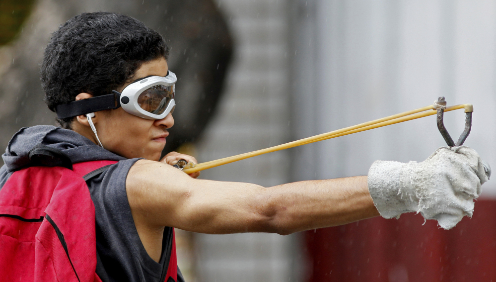 An anti-government protester launches marbles from a slingshot Friday at National Guards in Caracas, Venezuela.