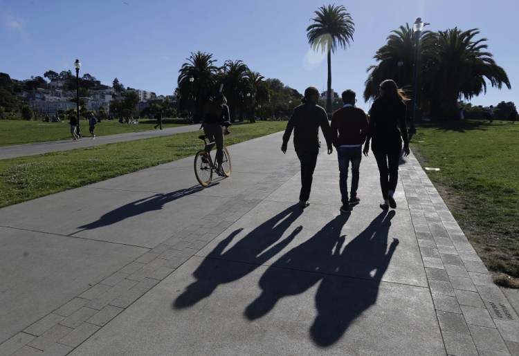 Mike Gougherty and Julie Rajagopal walk with their 16-year-old foster son from Eritrea at Dolores Park in San Francisco. She stayed up through the night calling government workers and charity officials in Cairo to speed the paperwork.