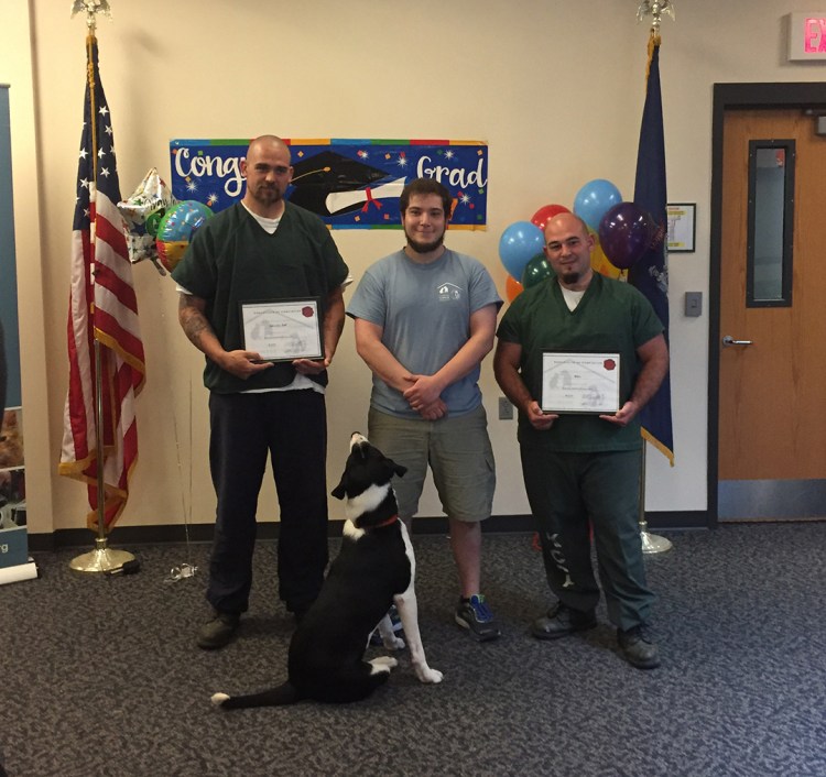 Norman Palmer, Mike Gould and Dustin Campbell, from left, pose with Border Collie mix Jake, one of the first Beyond the Bars graduates, at May’s ceremony at Two Bridges in Wiscasset.

