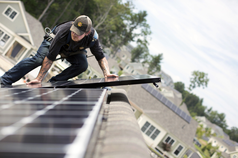 Jack Doherty, photovoltaic project manager for Portland-based ReVision Energy, installs a solar panel on a home at OceanView in Falmouth. The company, which employs almost 200 people, has installed panels on about 50 roofs within the development.
