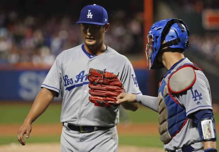 Los Angeles Dodgers starting pitcher Yu Darvish bumps fists with catcher Yasmani Grandal at the end of the third inning Friday en route to a victory over the host New York Mets.