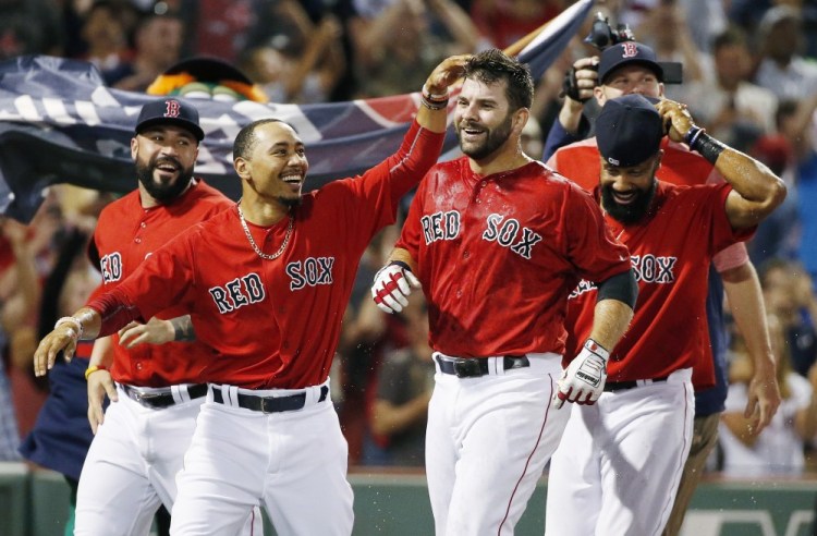 Boston's Mitch Moreland, center right, celebrates his walk-off home run with teammates, including Mookie Betts, second from left, in the 11th inning Friday night at Fenway Park.
