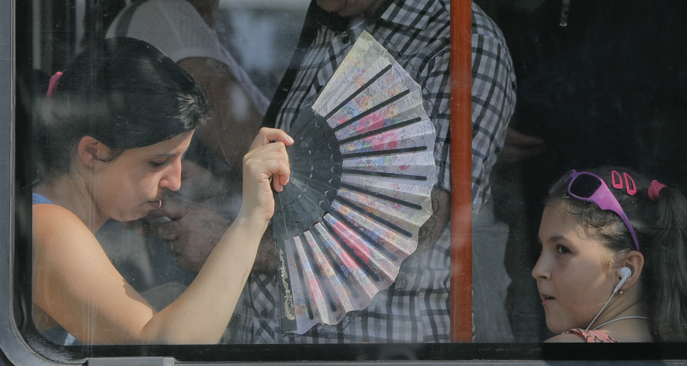 A woman uses a fan to cool herself and a child while ridding a tram in Bucharest, Romania, on Friday. Meteorologists there issued a "red code" heat alert for the next two days.