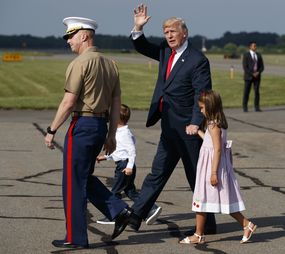 President Trump waves after arriving at Morristown Municipal Airport with grandchildren Arabella Kushner, right, and Joseph Kushner to begin a vacation at his Bedminster golf club on Friday, in Morristown, N.J. His staff will cycle in and out over the next 17 days.