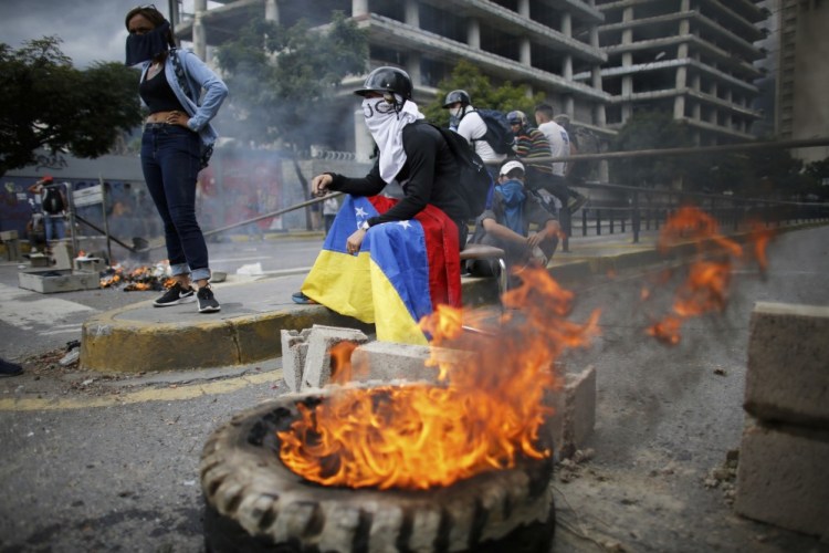 Masked anti-government demonstrators stand next to a burning barricade during a protest against the installation of a constitutional assembly Friday in Caracas, Venezuela.