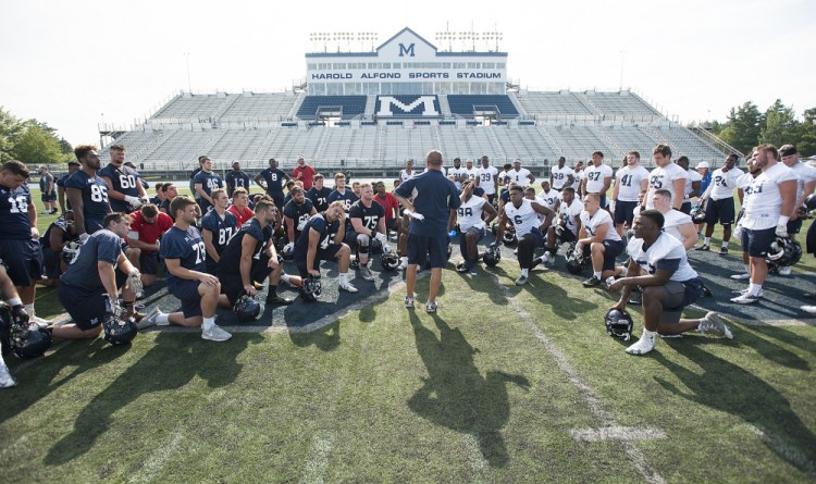 UMaine football coach Joe Harasymiak gathers his team for a post-practice talk Wednesday at Morse Field on the Orono campus. The second-year coach doesn't have a starting quarterback yet, and doesn't know whether he’ll have three of his best players available.