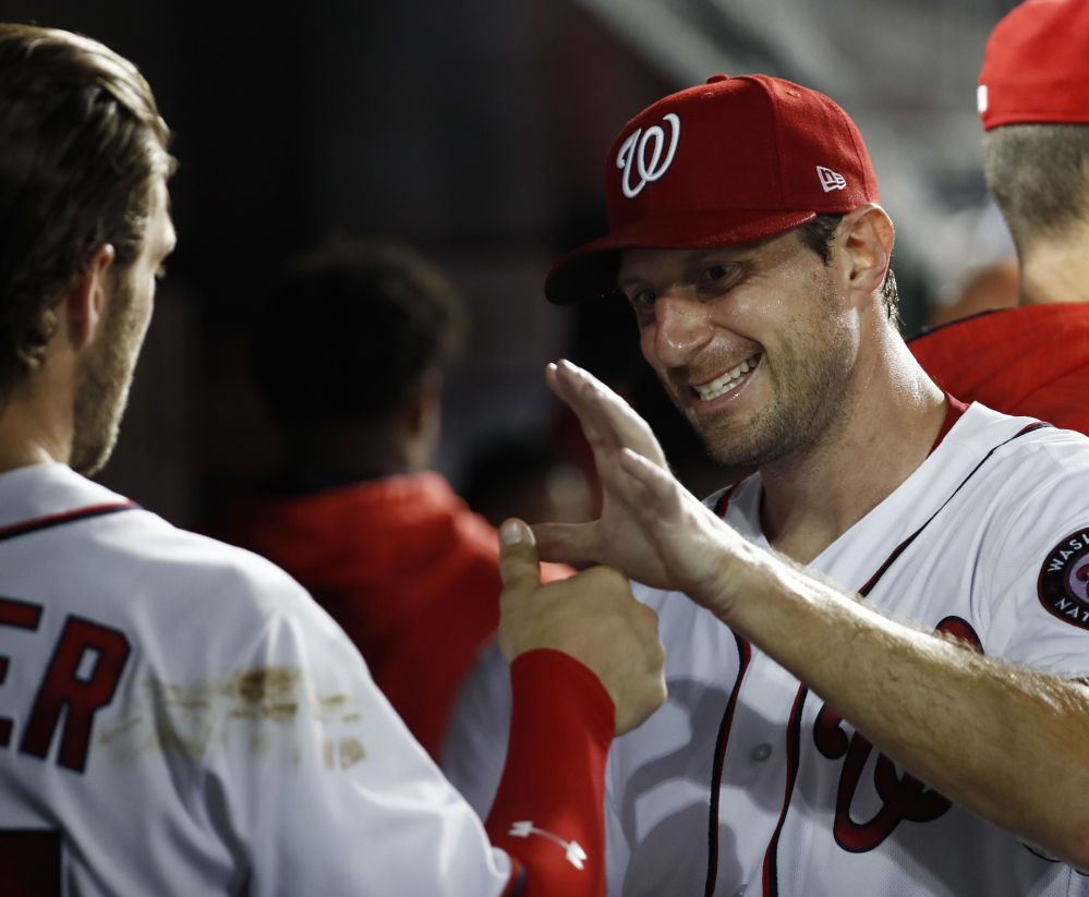Max Scherzer, right, celebrates with Bryce Harper after coming off the field in the seventh inning of the Nationals' 3-2 win over Miami on Monday. Scherzer pitched seven innings and Harper homered in the win.