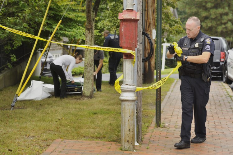 Portland police Sgt. Charles Libby removes police tape as medical staff and fellow officers prepare to remove the body of a man found at the intersection of Danforth and Vaughan streets in Portland on Tuesday morning. The death did not appear to be suspicious, police say.