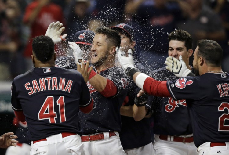 Yan Gomes, center, is mobbed by teammates Tuesday night after hitting a game-ending three-run homer to give the Cleveland Indians a 4-1 victory at home against the Colorado Rockies.
