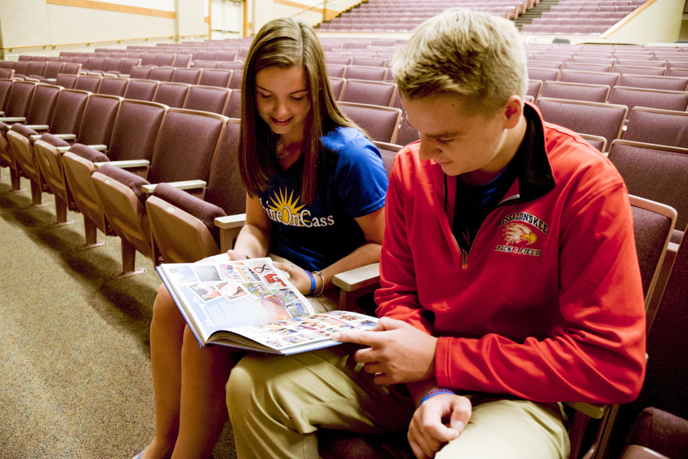 Shawna Oliver, a friend of Cassidy Charette and a member of the ShineOnCass Foundation board, and Charette's brother, Colby, look at a tribute to Cassidy in the Messalonskee High School yearbook on Wednesday at the high school.