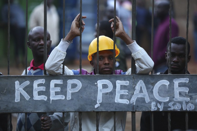 Kenyans in Kibera, Nairobi, lock themselves behind a gate with a Keep Peace sign as others burn tires to protest in support of opposition leader and presidential candidate Raila Odinga on Wednesday.