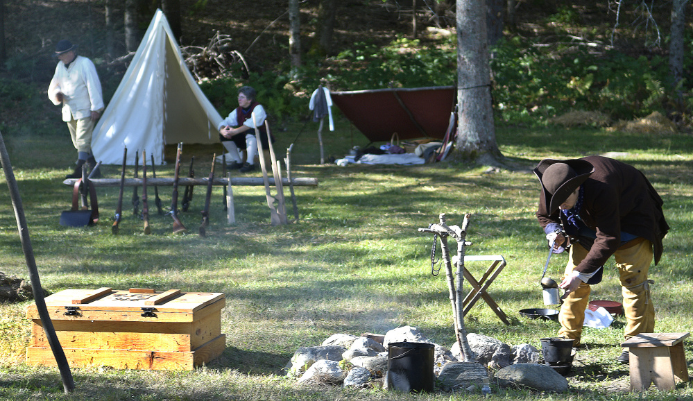 Ben Pierce of Vassalboro scoops coffee from a fire pit Sunday during the re-enactment held at the Pownalborough Court House in Dresden. The re-enactors portrayed militia members during the French and Indian War of 1755.