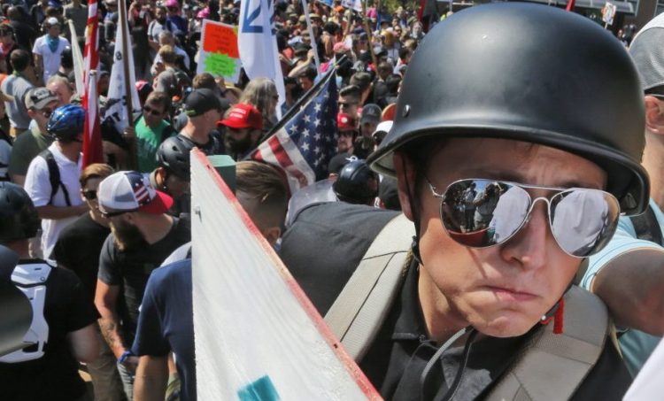 A white nationalist demonstrator with a helmet and shield walks into Lee Park in Charlottesville, Va., on Saturday. Hundreds of people chanted, threw punches and unleashed chemical sprays on each other.