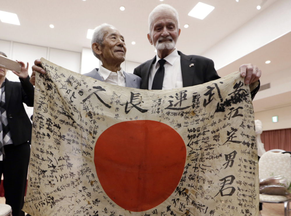 WWII veteran Marvin Strombo, right, and Tatsuya Yasue, 89, hold a Japanese flag that was owned by his brother Sadao Yasue, who was killed during World Work II