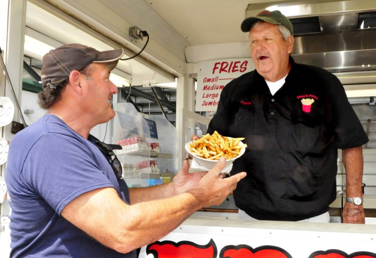 Stanley McGray, right, hands a jumbo order of fries to Mike McCourt at his Stan's French Fries stand at the Skowhegan State Fair on Tuesday. McCourt said he has enjoyed Stan's fries for decades. "I buy them here all the time cause I like the way they cook them," McCourt said.