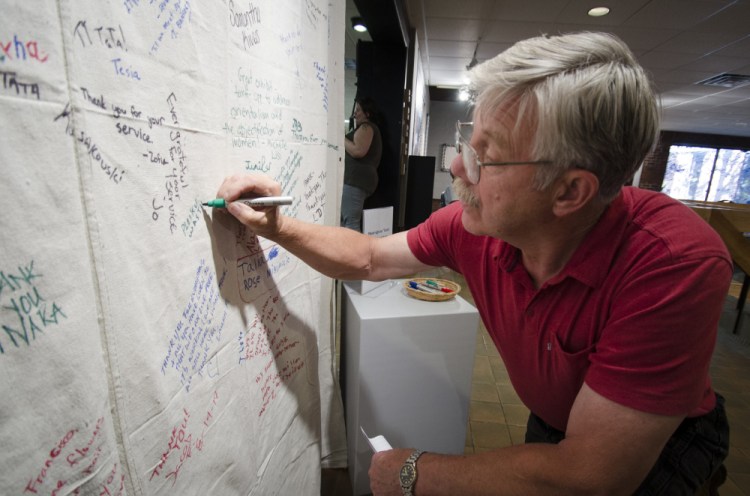 Vietnam War veteran Richard Sevigny, of North Waterboro, signs his name and adds "Pleikn, Vietnam, I was there, '66-'67" to a banner of remembrance at a Welcome Home ceremony held Thursday at the University of Maine at Augusta. The event was organized by the Bureau of Veteran's Affairs.