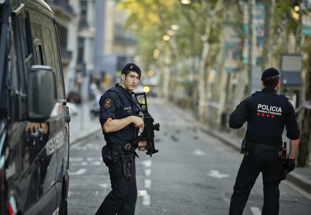 Armed police officers patrol a deserted street in Las Ramblas, in Barcelona, Spain, on Friday, a day after the driver of a white van sped down a pedestrian zone there, killing 13 people and wounding scores.