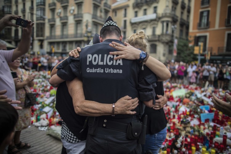 A policeman hugs a boy and his family, who he had helped during the terrorist attack, at a memorial to the victims on Las Ramblas, Barcelona, Spain, on Monday.