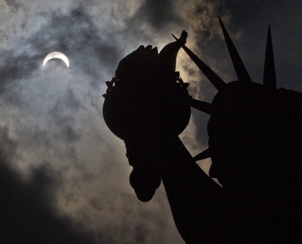 Day looks like night Monday afternoon in New York where the Statue of Liberty becomes a silhouette during the partial solar eclipse that briefly had much of the nation in the dark.