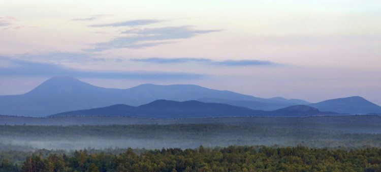 Early morning haze colors Mount Katahdin and its surrounding mountains, seen from land along Route 11 in Patten. The viewpoint is part of the Katahdin Woods and Waters scenic byway.