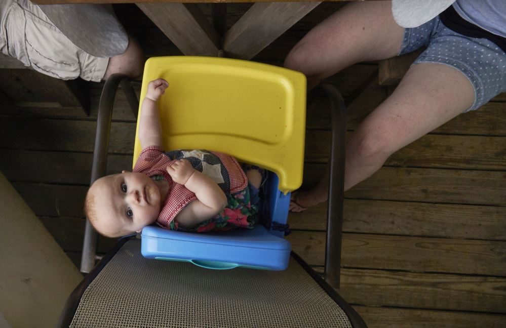  6-month-old Sydney Renda of Massachusetts looks up at a visitor while eating dinner with her parents on the porch of a vacation home in Ocean Park. 