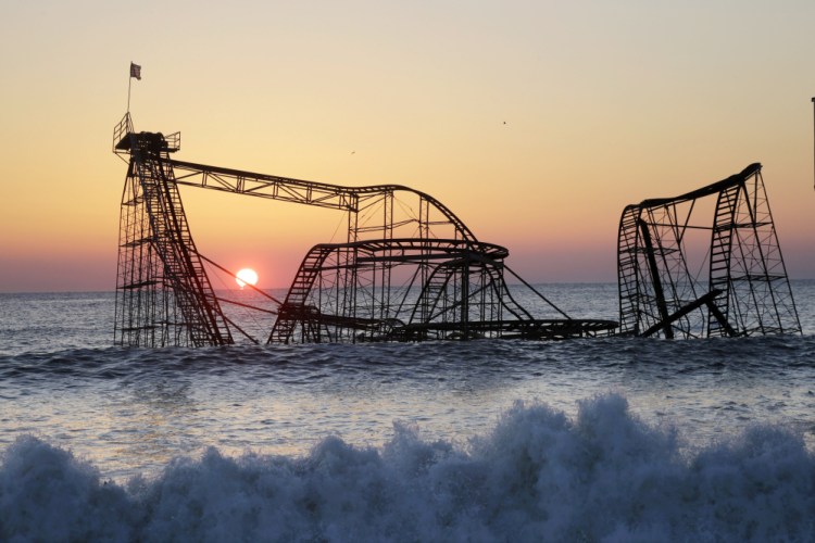 The sun rises behind the Jet Star Roller Coaster, sitting in the ocean on Feb. 25, 2013, after part of the Funtown Pier was destroyed during Superstorm Sandy in October 2012, in Seaside Heights, N.J.