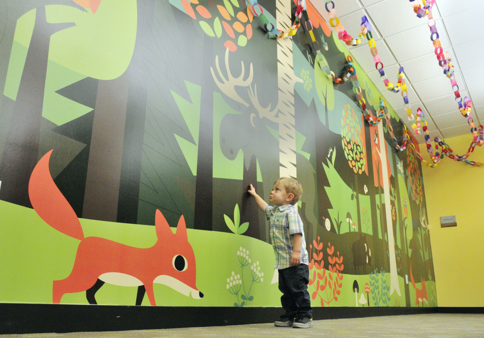 Weston Dube, 19 months old, points to a moose on the children's area wall at Lithgow Public Library in Augusta. There are nearly 3,000 paper rings hanging from the ceiling, each representing an hour of reading in the summer program.