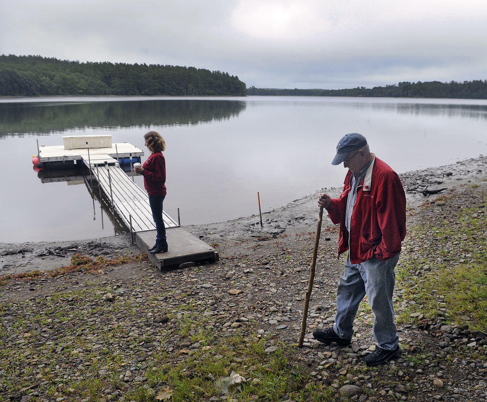 Stan Whittier walks on the shore of Clary Lake in Jefferson in 2015 while his daughter, Jane Roy, stands on the family's dock. It's been nearly five years since property owners in Jefferson and Whitefield appealed to the state to intervene over a low water level.