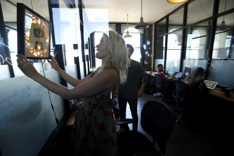 Pamela Fox, chief technology officer with Woebot, hangs a picture frame that contains the logo for the startup in San Francisco office. Woebot has created a chatbot that offers users cognitive behavioral therapy to help alleviate stress, anxiety and depression.