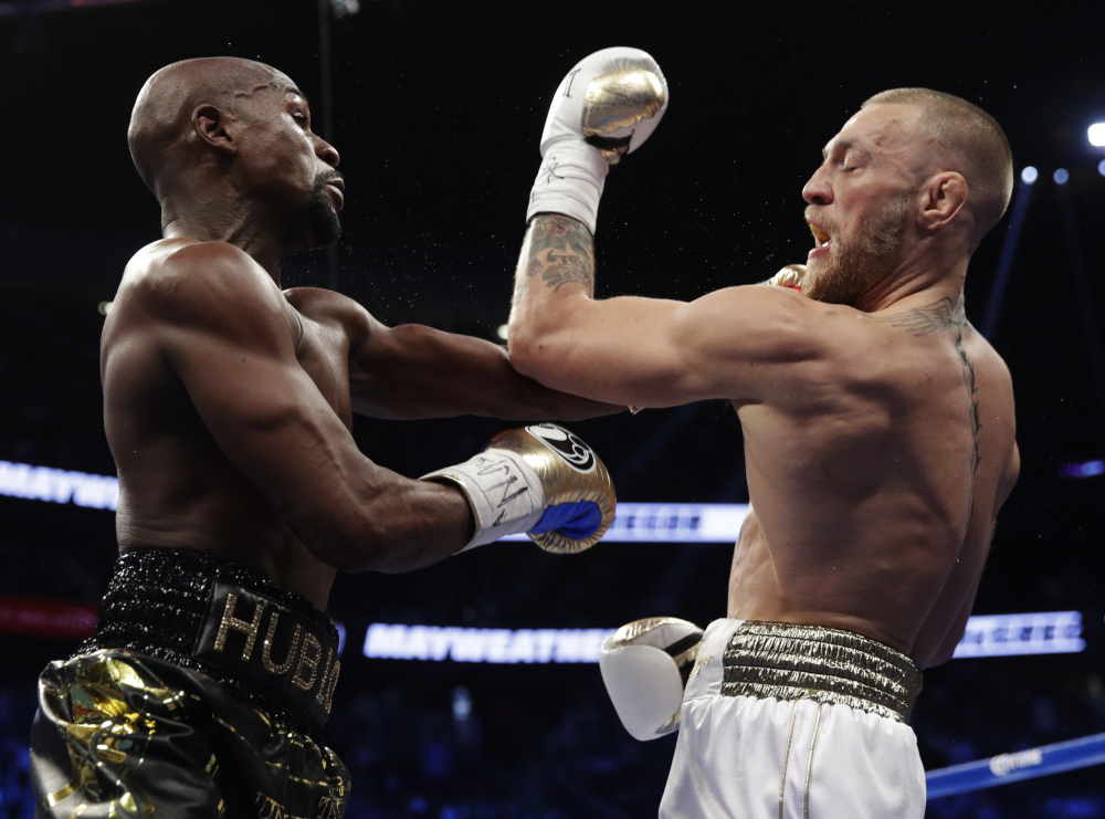 Floyd Mayweather Jr., left, hits Conor McGregor with a left cross on Saturday night in Las Vegas. Mayweather won the fight to move to 50-0 for his career.