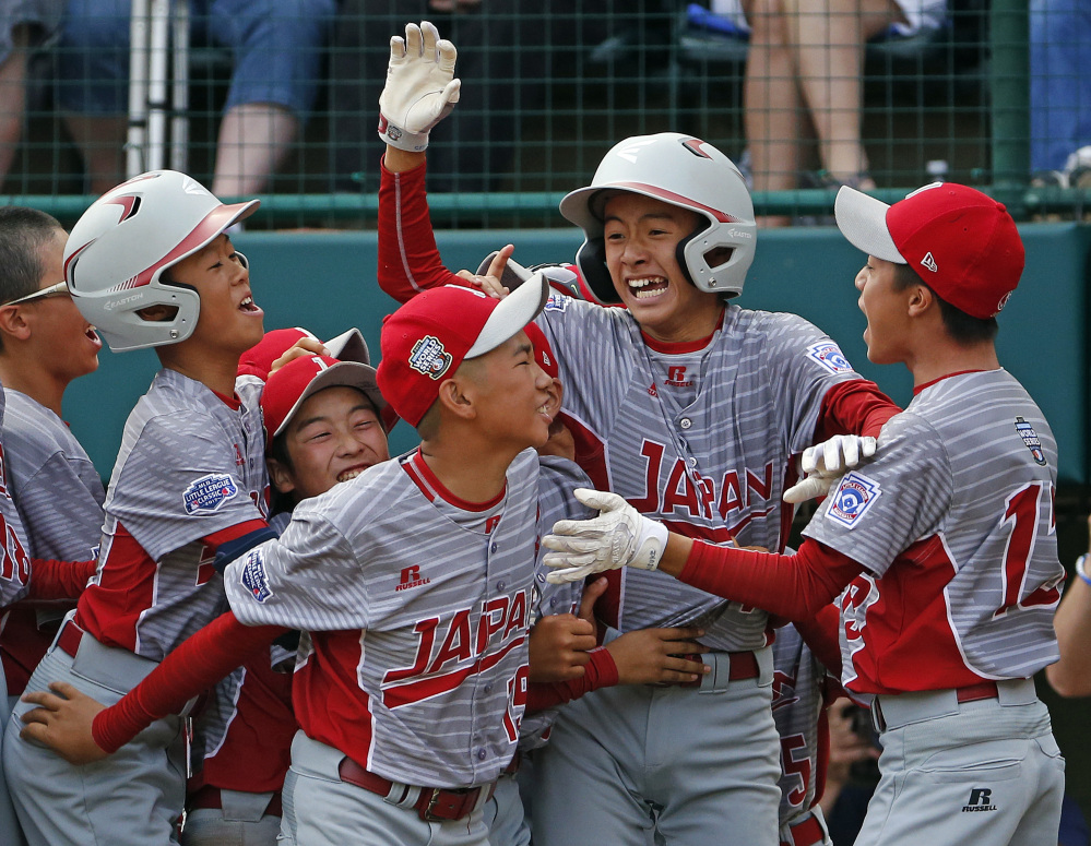 Japan's Seiya Arai, second from right, is surrounded by teammates after scoring the game-ending run against Texas in a 12-2 victory in the final of the Little League World Series.